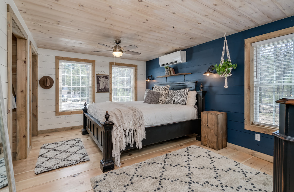 Photo of a country bedroom in Portland Maine with blue walls, light hardwood floors and beige floor.