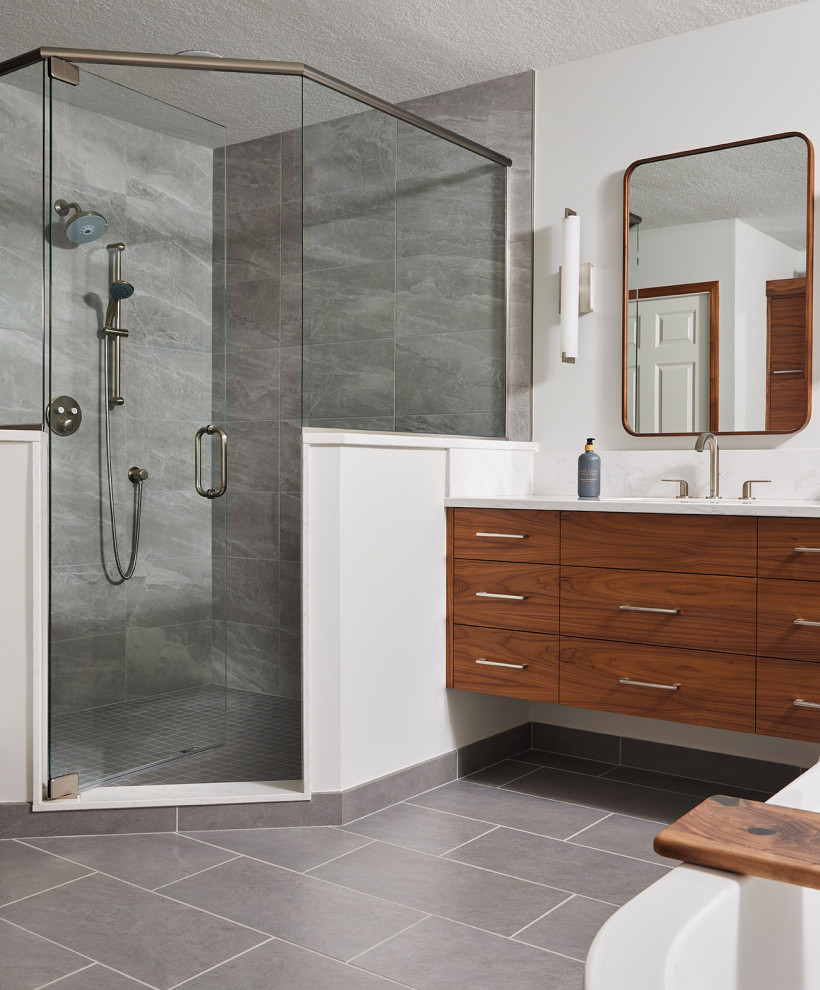 Large modern bathroom in Minneapolis with flat-panel cabinets, medium wood cabinets, a corner shower, grey tiles, porcelain tiles, white walls, porcelain flooring, a submerged sink, engineered stone worktops, a hinged door, white worktops, a single sink and a floating vanity unit.