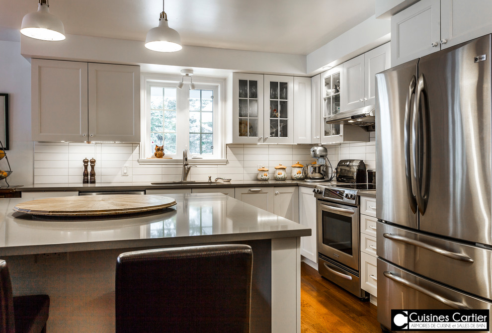 Example of a large transitional medium tone wood floor eat-in kitchen design in Montreal with a double-bowl sink, shaker cabinets, white cabinets, quartzite countertops, white backsplash, ceramic backsplash, stainless steel appliances and an island