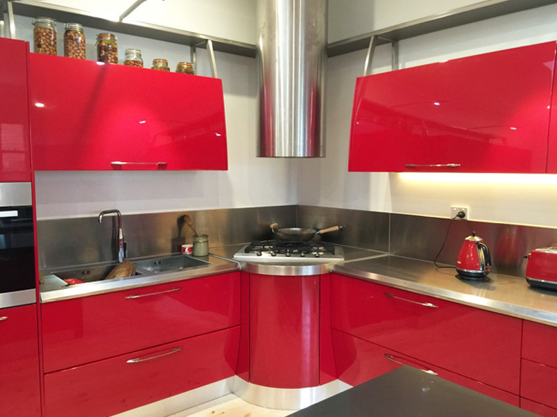 Inspiration for a mid-sized contemporary l-shaped eat-in kitchen in Melbourne with a double-bowl sink, raised-panel cabinets, red cabinets, stainless steel benchtops, metallic splashback, stainless steel appliances, light hardwood floors and with island.