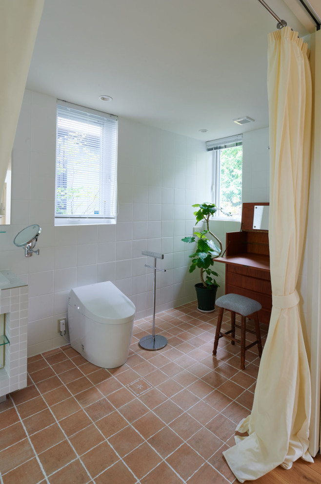 Exemple d'un WC et toilettes scandinave de taille moyenne avec un carrelage blanc et tomettes au sol.
