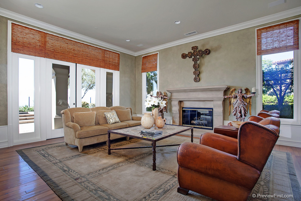 Photo of a large transitional enclosed living room in Orange County with beige walls, medium hardwood floors, a standard fireplace and a concrete fireplace surround.