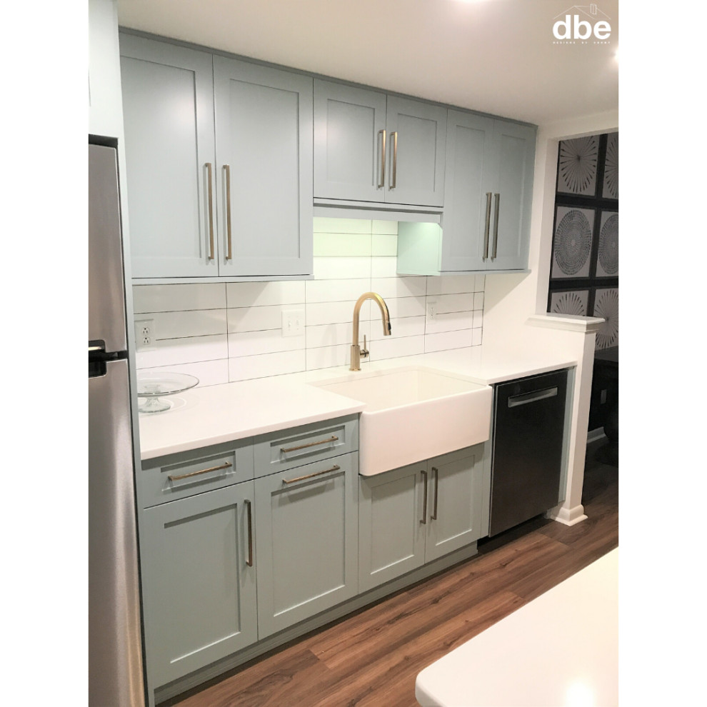 Small transitional galley vinyl floor and brown floor kitchen photo with a farmhouse sink, shaker cabinets, blue cabinets, quartz countertops, white backsplash, subway tile backsplash, stainless steel appliances, no island and white countertops