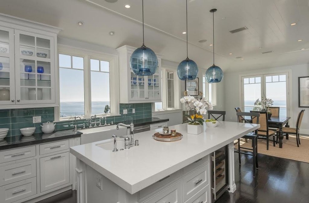 Eat-in kitchen - large transitional galley laminate floor and brown floor eat-in kitchen idea in Los Angeles with a drop-in sink, glass-front cabinets, white cabinets, solid surface countertops, blue backsplash, ceramic backsplash, stainless steel appliances and an island