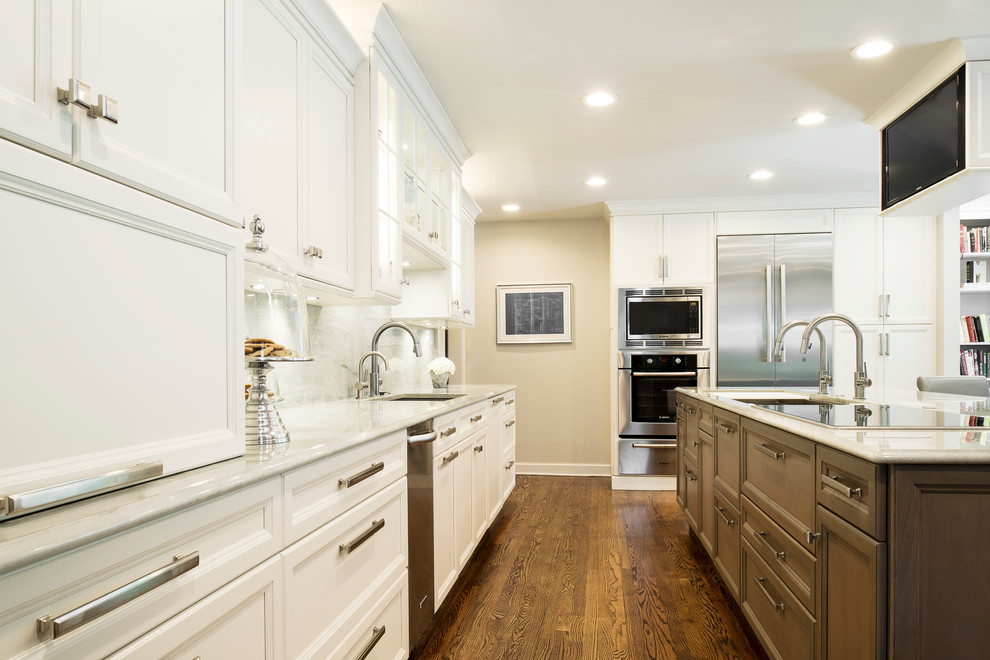 Kitchen - large transitional single-wall medium tone wood floor and brown floor kitchen idea in Denver with an undermount sink, stainless steel appliances, white backsplash, stone slab backsplash, recessed-panel cabinets, white cabinets and an island