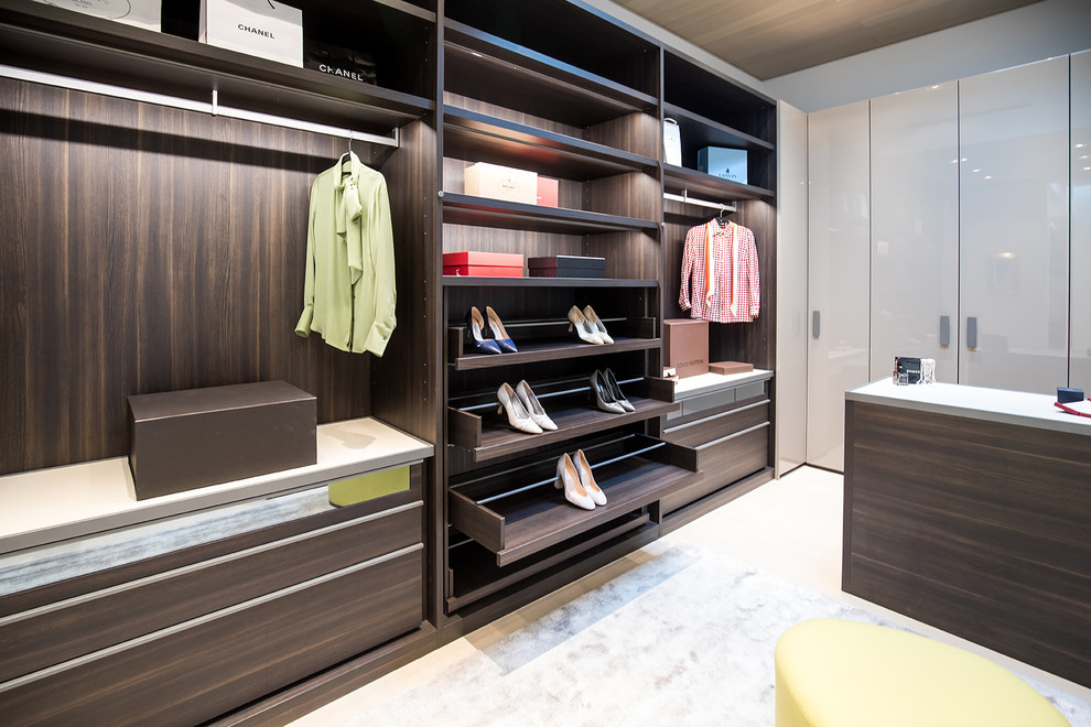 Photo of a large modern gender-neutral dressing room in Los Angeles with open cabinets, dark wood cabinets and recessed.