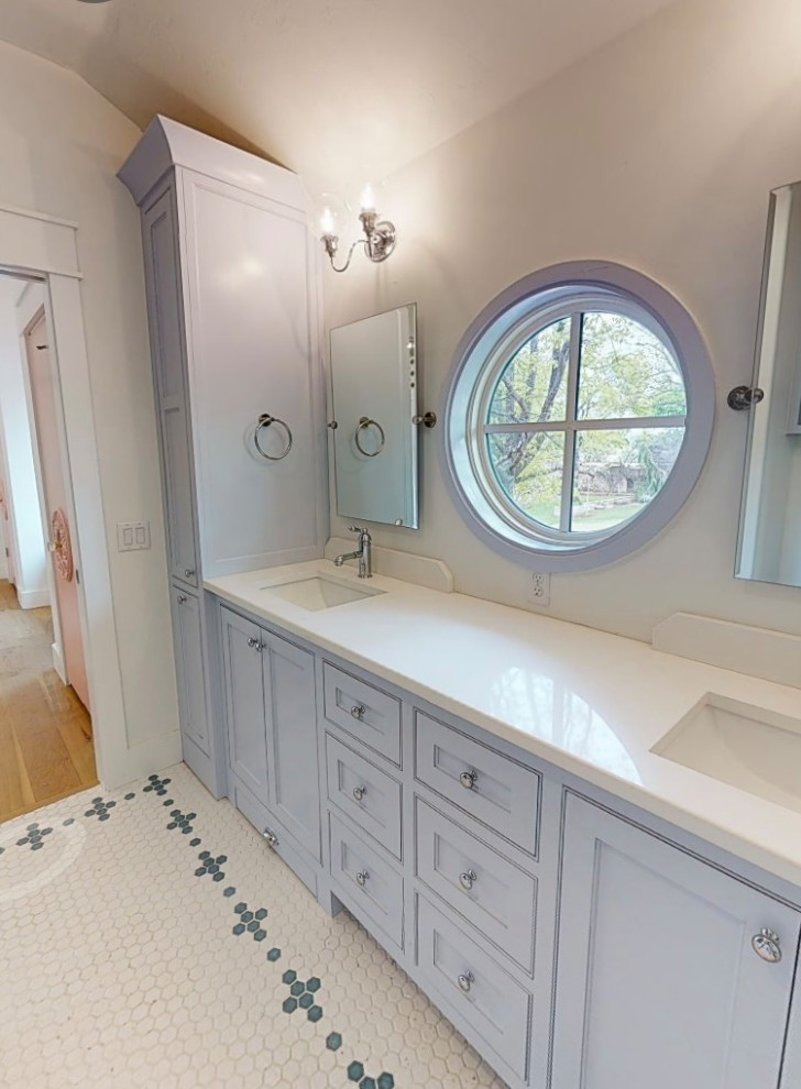 Photo of a medium sized traditional family bathroom in Oklahoma City with beaded cabinets, blue cabinets, an alcove bath, a shower/bath combination, a two-piece toilet, blue tiles, ceramic tiles, white walls, mosaic tile flooring, a submerged sink, engineered stone worktops, multi-coloured floors, white worktops, a laundry area, double sinks and a built in vanity unit.