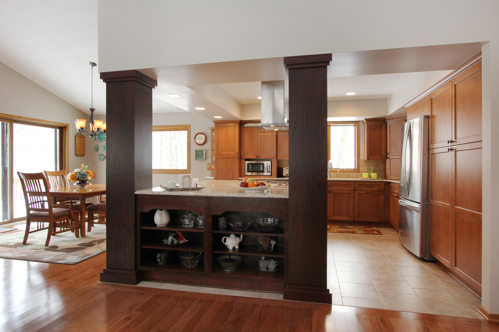 Photo of a mid-sized traditional u-shaped open plan kitchen in Grand Rapids with flat-panel cabinets, medium wood cabinets, granite benchtops, brown splashback, ceramic splashback, stainless steel appliances, ceramic floors and a double-bowl sink.