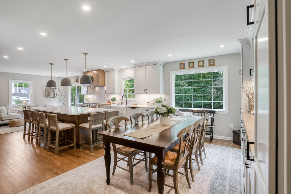 Photo of an expansive traditional l-shaped kitchen/diner in DC Metro with a belfast sink, recessed-panel cabinets, white cabinets, engineered stone countertops, white splashback, white appliances, an island and white worktops.