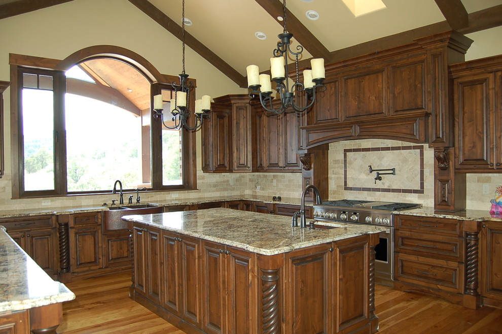 Large mountain style u-shaped medium tone wood floor eat-in kitchen photo in Denver with a farmhouse sink, raised-panel cabinets, dark wood cabinets, granite countertops, beige backsplash, ceramic backsplash, stainless steel appliances and an island