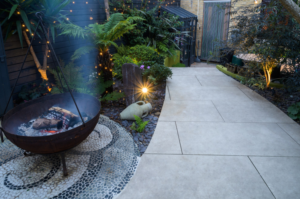 Photo of a medium sized world-inspired back garden in London with a fire feature and decorative stones.