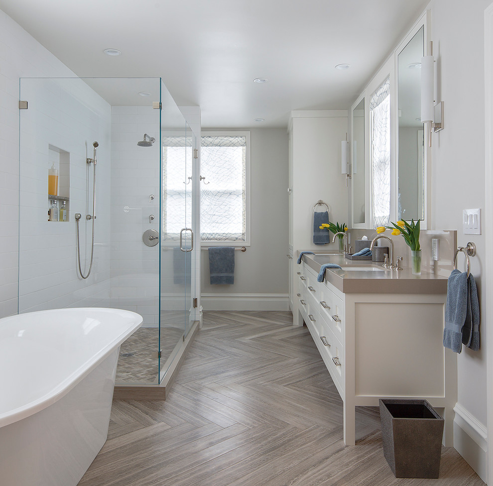 This is an example of a transitional master bathroom in San Francisco with shaker cabinets, white cabinets, a freestanding tub, white tile, grey walls, an undermount sink and a hinged shower door.
