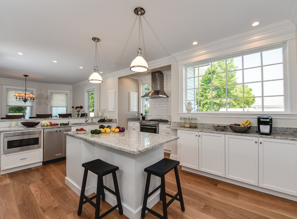 Inspiration for a large eat-in kitchen in Boston with white cabinets, granite benchtops, white splashback, stainless steel appliances, light hardwood floors and multiple islands.