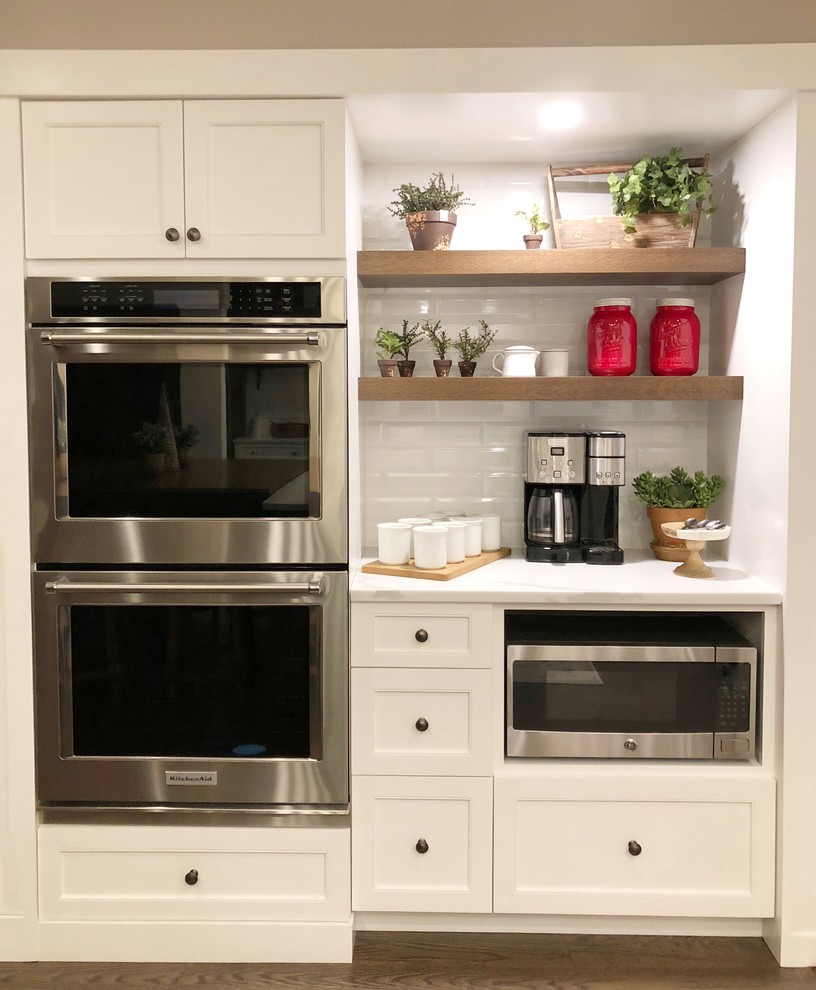 Eat-in kitchen - huge transitional dark wood floor and brown floor eat-in kitchen idea with an undermount sink, shaker cabinets, white cabinets, quartz countertops, white backsplash, porcelain backsplash, stainless steel appliances, an island and white countertops