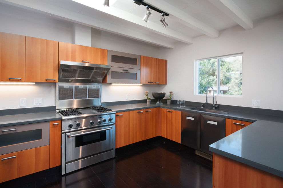 Mid-sized midcentury u-shaped open plan kitchen in San Francisco with an undermount sink, flat-panel cabinets, brown cabinets, quartz benchtops, grey splashback, stainless steel appliances, dark hardwood floors, a peninsula, brown floor and grey benchtop.