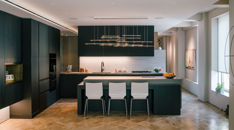 Inspiration for a large contemporary l-shaped kitchen in New York with an undermount sink, flat-panel cabinets, black cabinets, panelled appliances, light hardwood floors, with island, beige floor, concrete benchtops, grey splashback and stone slab splashback.