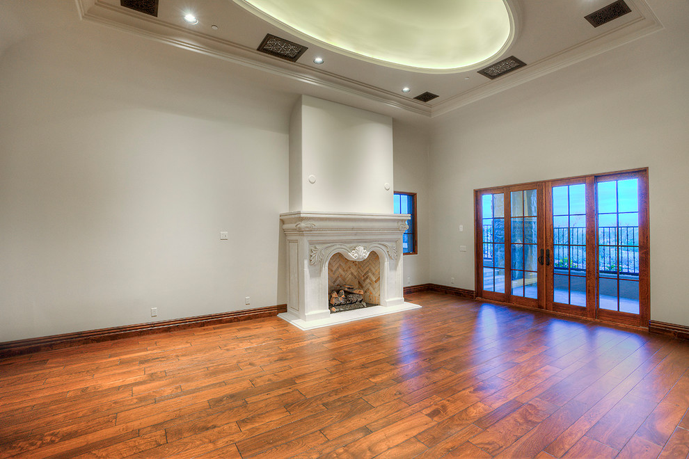 Expansive traditional master bedroom in Phoenix with a standard fireplace, a stone fireplace surround, white walls and dark hardwood floors.