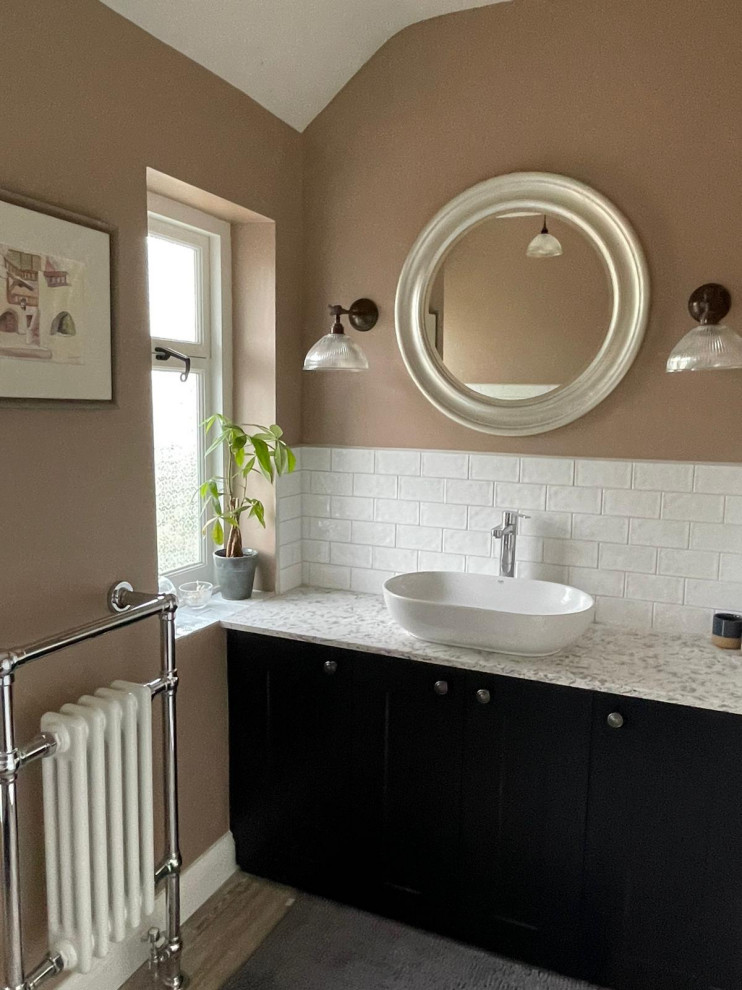 Photo of a mid-sized traditional kids bathroom with shaker cabinets, black cabinets, a claw-foot tub, a shower/bathtub combo, a two-piece toilet, white tile, ceramic tile, pink walls, wood-look tile, a vessel sink, marble benchtops, grey floor, white benchtops, a single vanity and a built-in vanity.