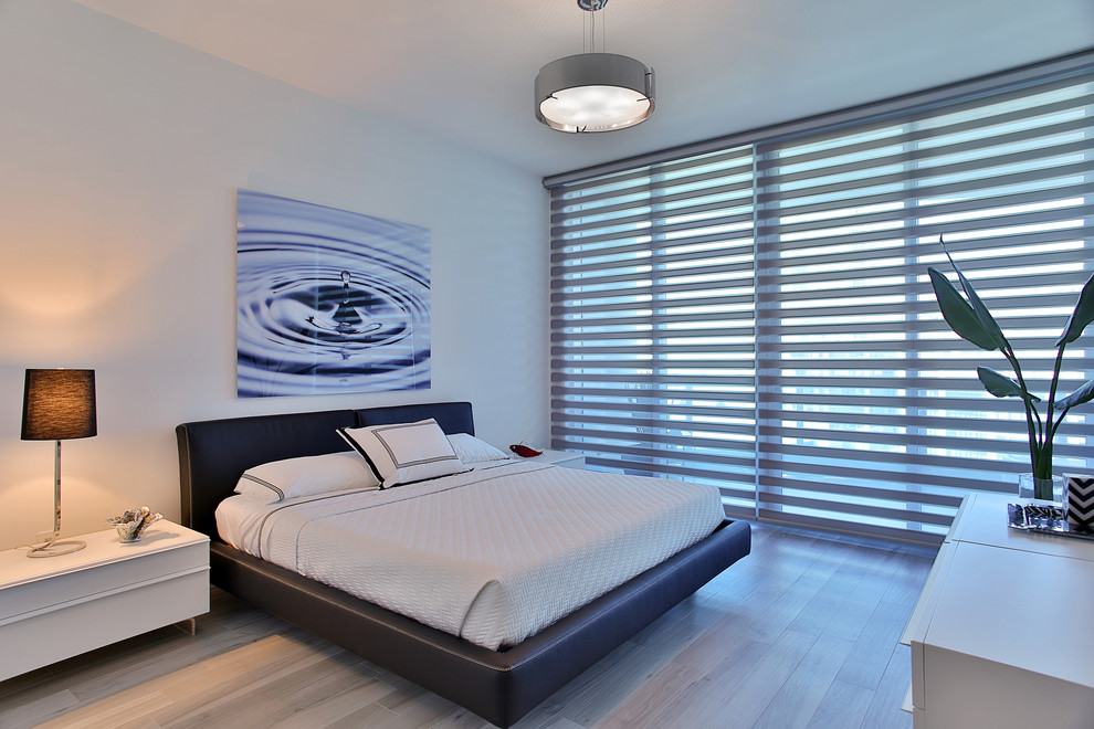 Large contemporary bedroom in Miami with white walls and porcelain floors.