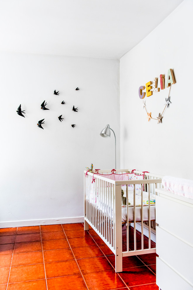 This is an example of a small mediterranean nursery for girls in Madrid with white walls and terra-cotta floors.