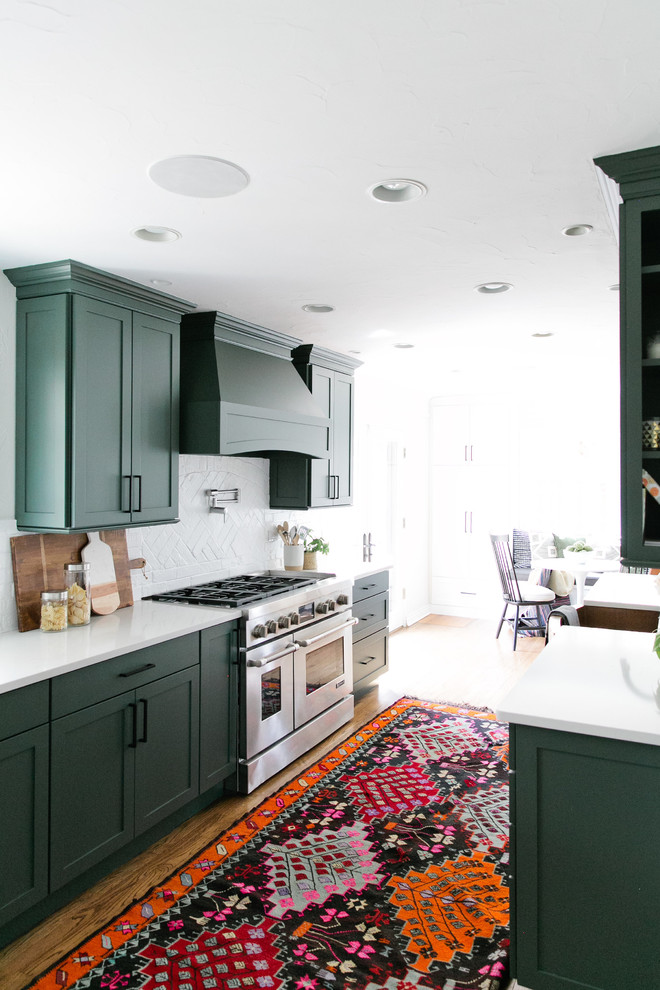 Inspiration for a mid-sized transitional galley medium tone wood floor and brown floor eat-in kitchen remodel in Denver with a farmhouse sink, shaker cabinets, green cabinets, quartz countertops, white backsplash, brick backsplash, stainless steel appliances, a peninsula and white countertops