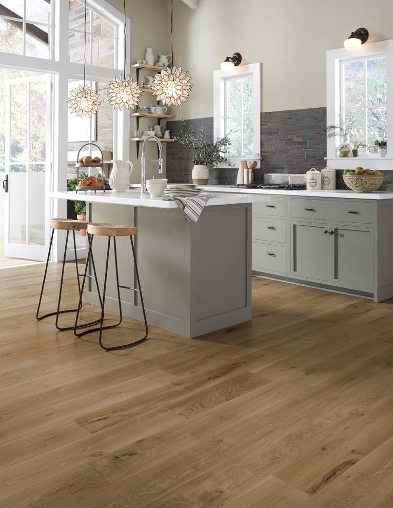 Kitchen - large transitional medium tone wood floor and brown floor kitchen idea with an undermount sink, shaker cabinets, gray cabinets, quartz countertops, gray backsplash, stone tile backsplash and an island