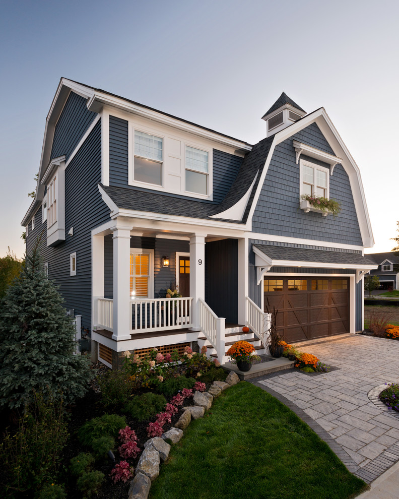 This is an example of a mid-sized arts and crafts two-storey blue house exterior in New York with vinyl siding, a gambrel roof and a shingle roof.