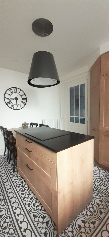 Small transitional u-shaped cement tile floor, black floor and tray ceiling eat-in kitchen photo in Toulouse with an integrated sink, louvered cabinets, light wood cabinets, white backsplash, ceramic backsplash, paneled appliances, an island and black countertops