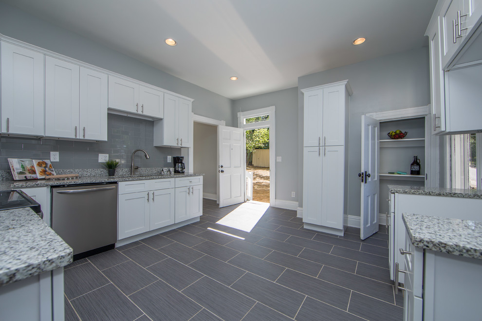 This is an example of a mid-sized transitional kitchen in Richmond with an undermount sink, shaker cabinets, white cabinets, granite benchtops, grey splashback, ceramic splashback, stainless steel appliances, porcelain floors, no island and grey floor.