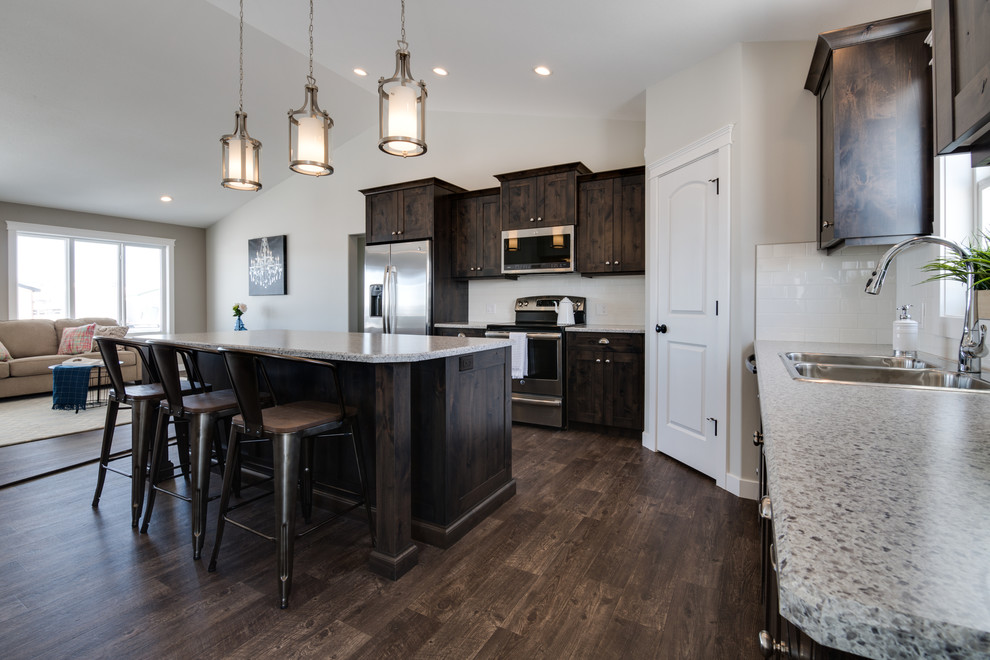 Example of a mid-sized transitional l-shaped open concept kitchen design with shaker cabinets, dark wood cabinets, laminate countertops, stainless steel appliances and an island