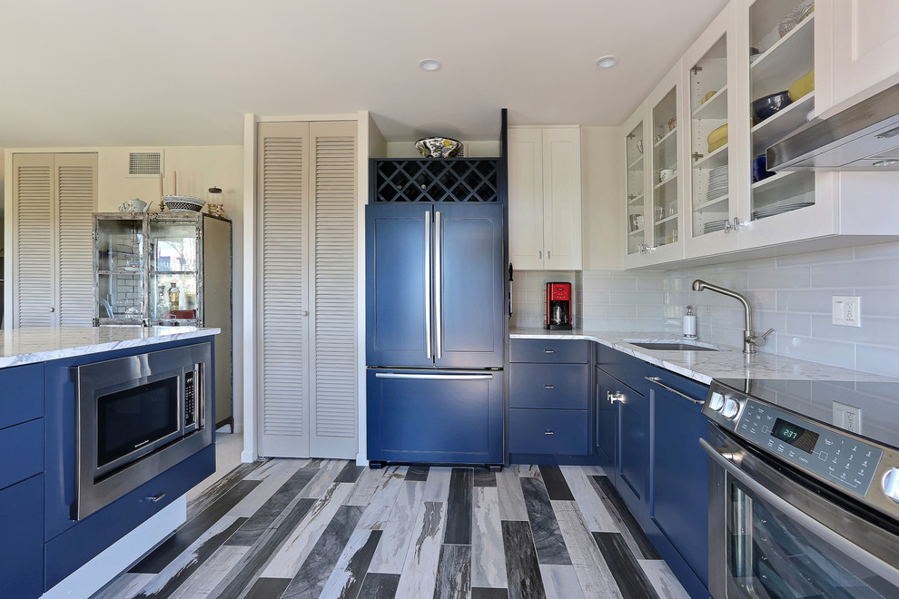 This is an example of a transitional kitchen in Denver with an undermount sink, shaker cabinets, blue cabinets, marble benchtops, white splashback, subway tile splashback, stainless steel appliances and porcelain floors.