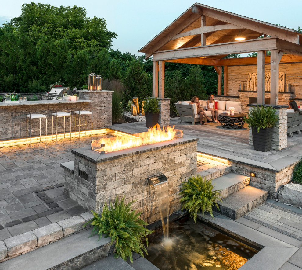Photo of a large transitional backyard patio in New York with concrete pavers, a pergola and an outdoor kitchen.