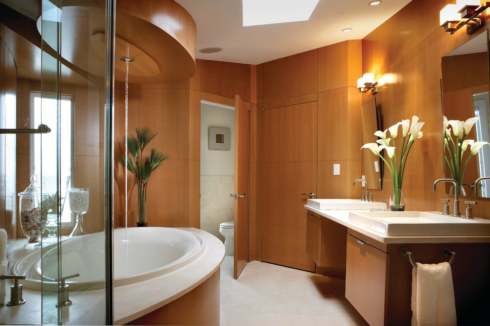 This is an example of a contemporary master bathroom in Philadelphia with flat-panel cabinets, medium wood cabinets, a drop-in tub, a drop-in sink and an enclosed toilet.