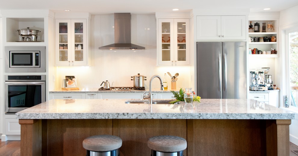 Inspiration for a mid-sized transitional eat-in kitchen in Vancouver with an undermount sink, shaker cabinets, white cabinets, quartzite benchtops, white splashback, porcelain splashback, stainless steel appliances, medium hardwood floors and with island.
