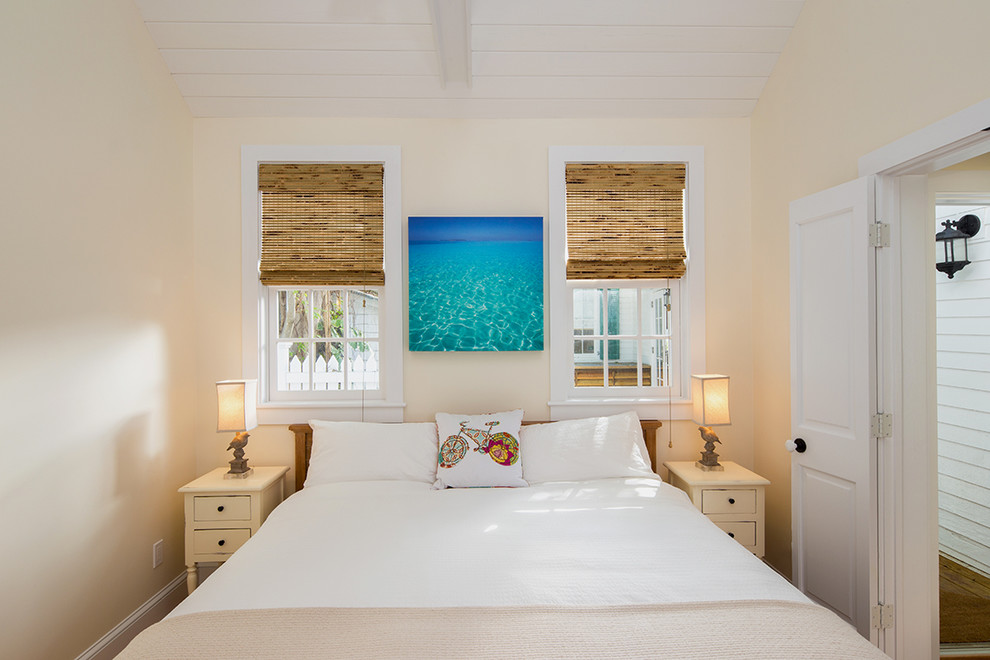 Design ideas for a beach style guest bedroom in Miami with beige walls and light hardwood floors.