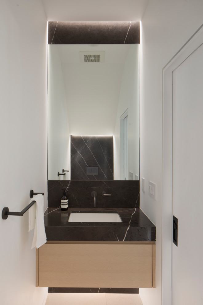 Идея дизайна: туалет среднего размера в стиле модернизм с плоскими фасадами, светлыми деревянными фасадами, инсталляцией, черной плиткой, мраморной плиткой, белыми стенами, полом из известняка, врезной раковиной, мраморной столешницей, белым полом, черной столешницей и подвесной тумбой