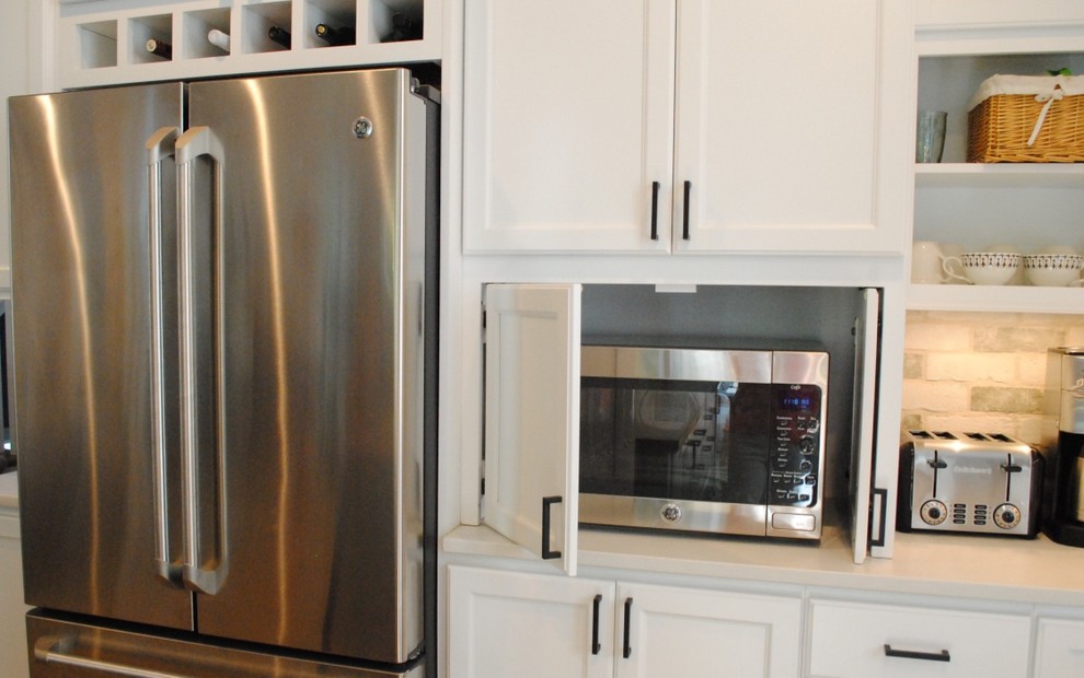 Example of a transitional light wood floor eat-in kitchen design in Baltimore with a farmhouse sink, flat-panel cabinets, white cabinets, quartz countertops, white backsplash, stone tile backsplash, stainless steel appliances and an island