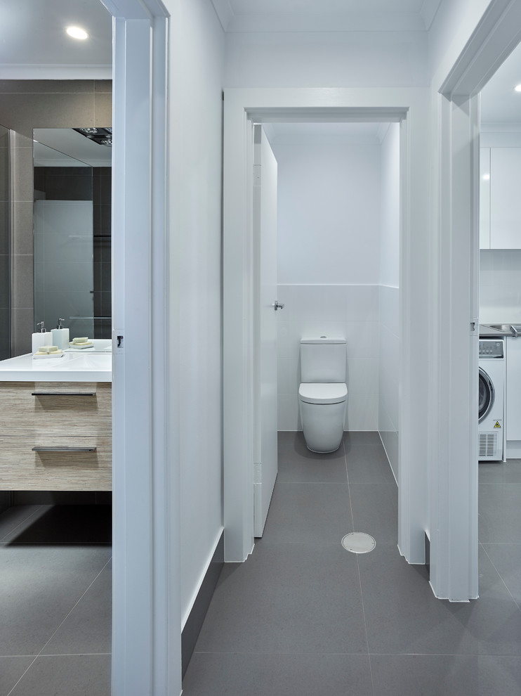 Contemporary bathroom in Other with a two-piece toilet, gray tile and white walls.