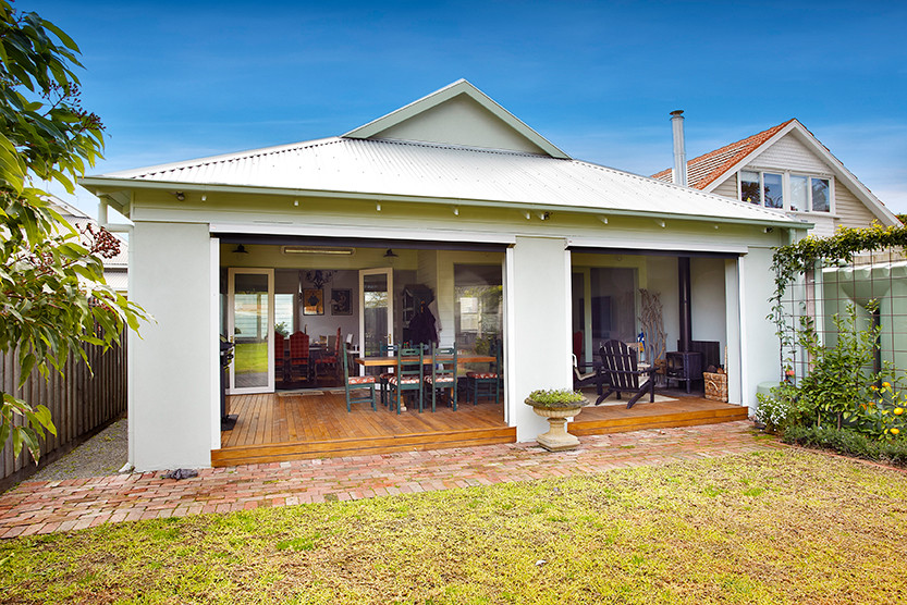 This is an example of a mid-sized contemporary exterior in Melbourne with light hardwood floors, a wood stove, a metal fireplace surround and a standard ceiling.