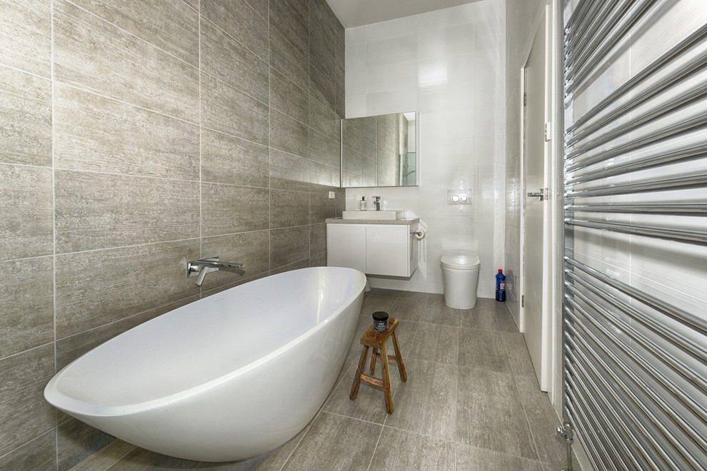 Photo of a mid-sized contemporary bathroom in Melbourne with flat-panel cabinets, white cabinets, a freestanding tub, a one-piece toilet and a vessel sink.