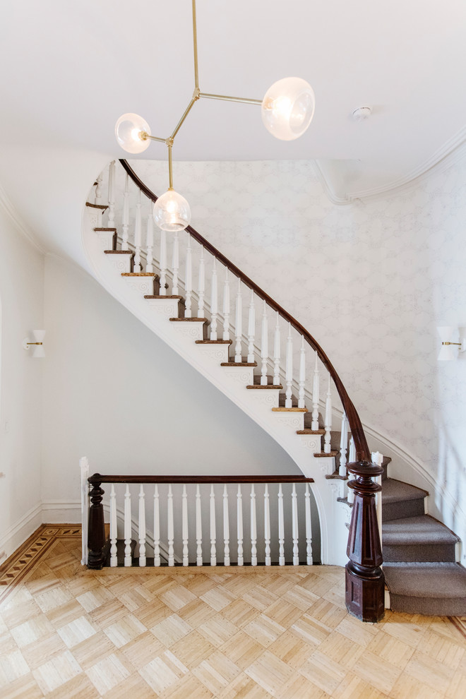 Photo of a transitional wood curved staircase in New York with wood risers and wood railing.