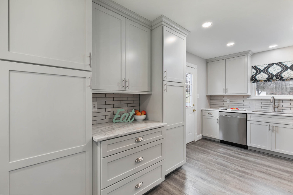 Photo of a mid-sized contemporary eat-in kitchen in Baltimore with an undermount sink, shaker cabinets, grey cabinets, quartzite benchtops, white splashback, subway tile splashback, stainless steel appliances, vinyl floors, grey floor and white benchtop.