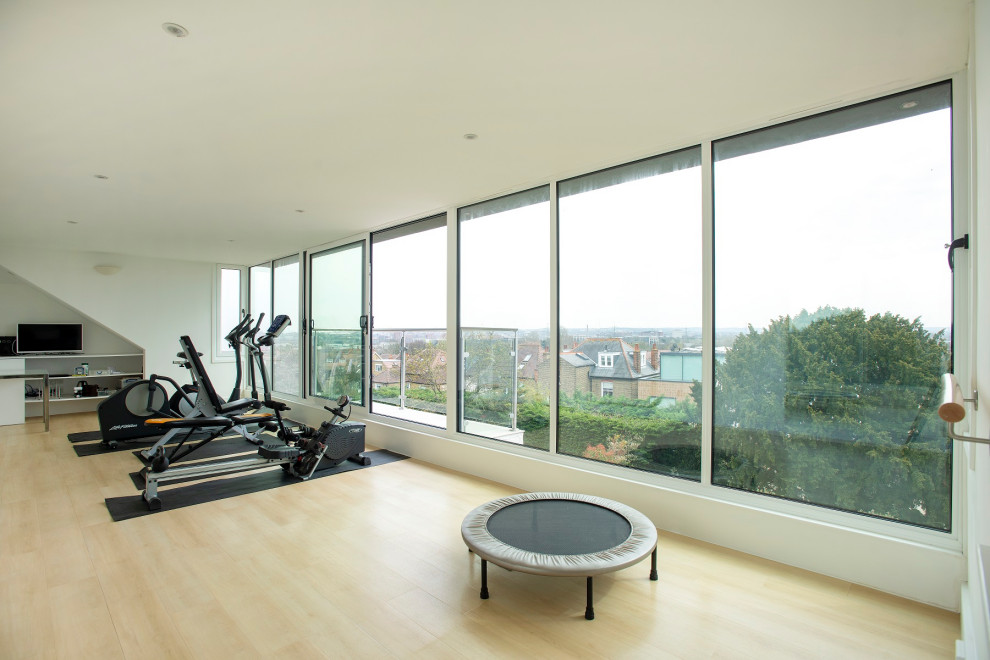 This is an example of a large contemporary multi-use home gym in London with white walls, laminate floors and yellow floors.