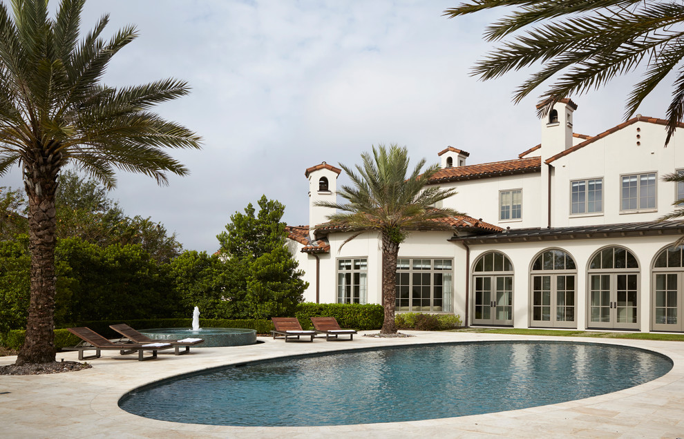 Photo of an expansive mediterranean backyard custom-shaped pool in Houston with a water feature and tile.
