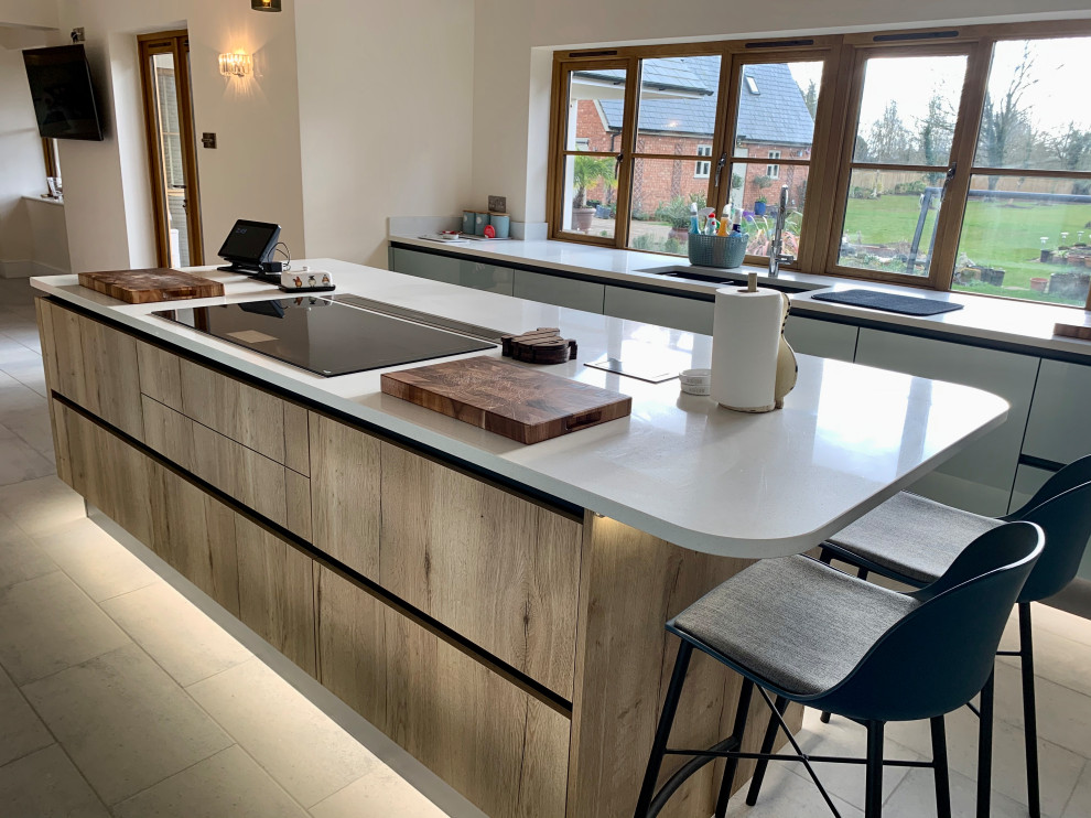 Large industrial kitchen in Buckinghamshire with flat-panel cabinets, quartzite benchtops, stainless steel appliances, with island, grey floor, white benchtop and medium wood cabinets.