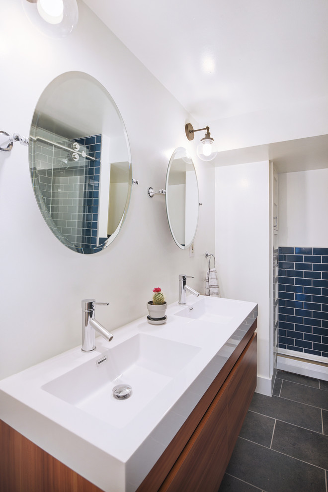 This is an example of a mid-sized transitional master bathroom in Denver with flat-panel cabinets, medium wood cabinets, blue tile, subway tile, white walls, porcelain floors, an integrated sink, engineered quartz benchtops, black floor and white benchtops.