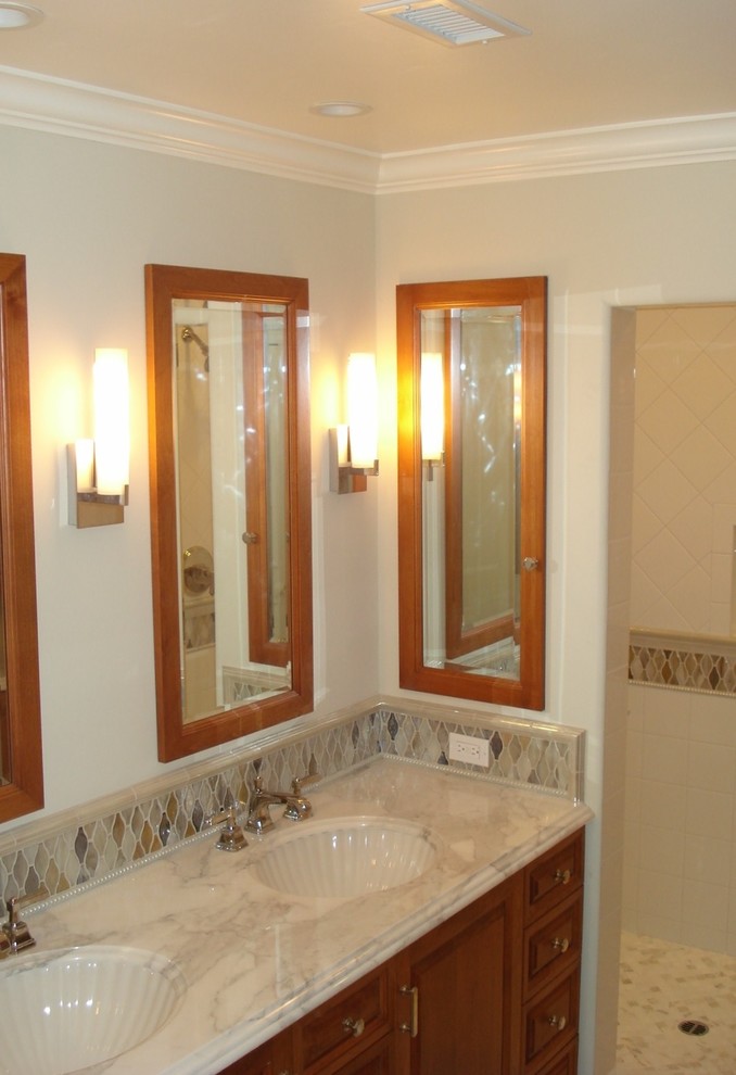Inspiration for a mid-sized traditional bathroom in Orange County with raised-panel cabinets, medium wood cabinets, an open shower, beige tile, ceramic tile, white walls, an integrated sink, mosaic tile floors, onyx benchtops, beige floor, an open shower, beige benchtops, a niche, a double vanity and a built-in vanity.