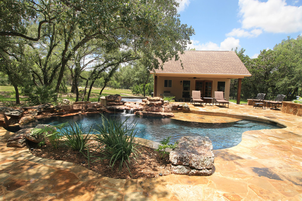 Example of a mid-sized mountain style backyard stone and custom-shaped natural hot tub design in Austin