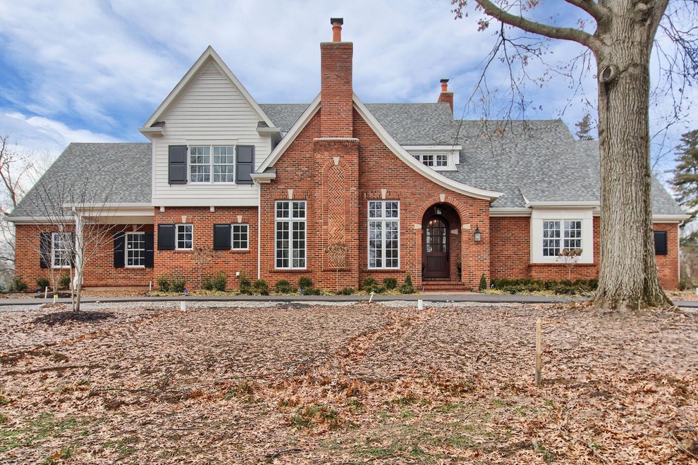 Traditional two-storey brick red house exterior in St Louis with a gable roof and a shingle roof.