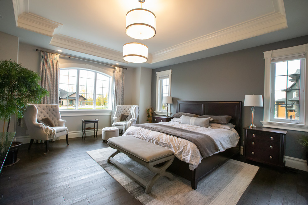 This is an example of a large transitional master bedroom in Edmonton with grey walls, dark hardwood floors and brown floor.